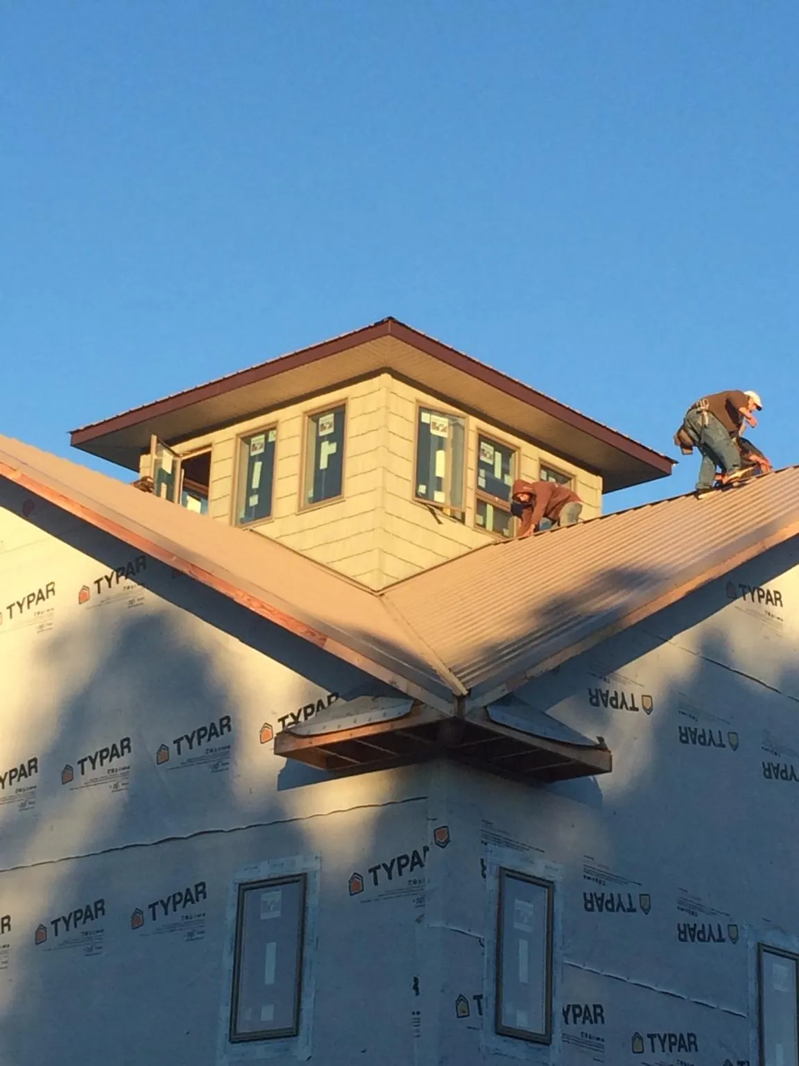 Roofers working around a rooftop cupola on a new metal roof at sunset — Roof Waterproofing in Jefferson by Roofing Brothers